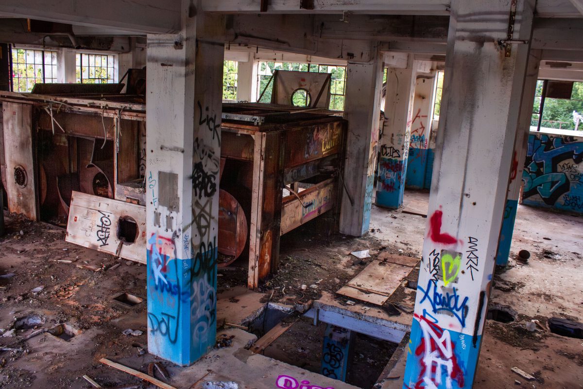 Abandoned Fruen Mill interior in Minneapolis with graffiti-covered concrete pillars and rusted industrial equipment.