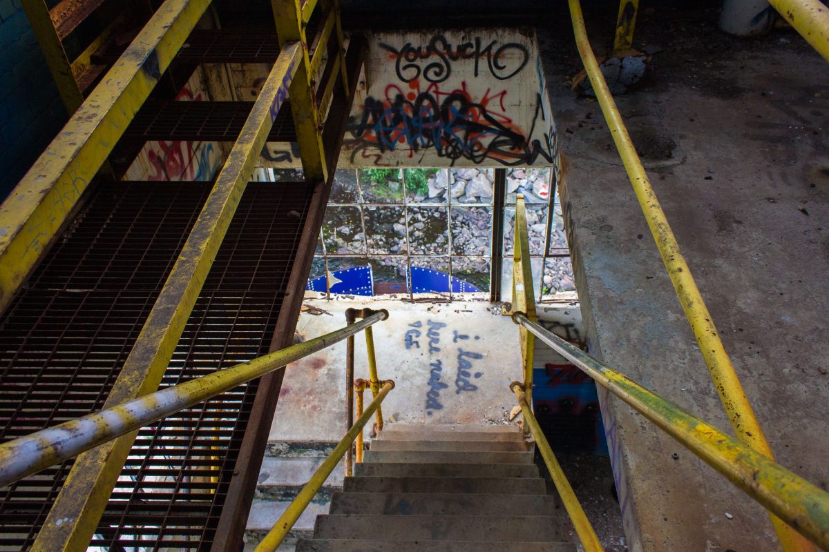 Yellow metal staircase descending into the abandoned Fruen Mill grain processing facility in Minneapolis.