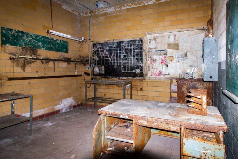 Abandoned Testing Lab, Schmidt Brewery, St. Paul 1 Abandoned classroom or institutional kitchen with deteriorating yellow tile walls and rust-covered metal tables and benches.