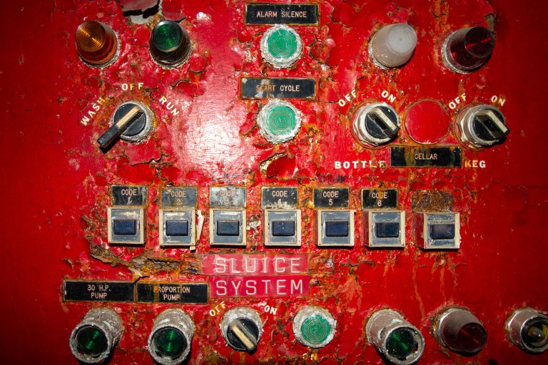 Sluice System Control Panel, Schmidt Brewery, St. Paul 3 Weathered red control panel from Schmidt's Brewery in St. Paul with corroded switches, gauges, and labeled codes for the sluice