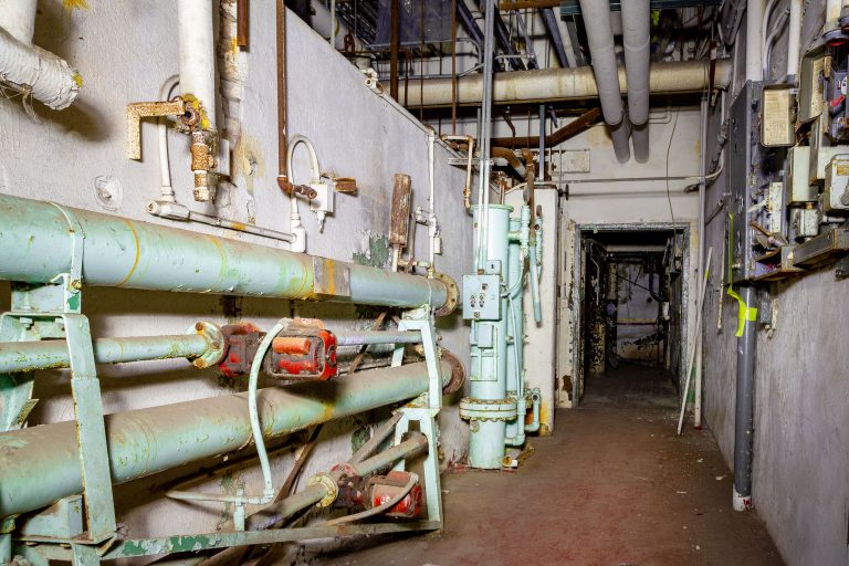 Utility Corridor, Former Schmidt Brewery, St. Paul 4 Corroded pipes and industrial equipment line a narrow corridor inside an abandoned brewery facility.