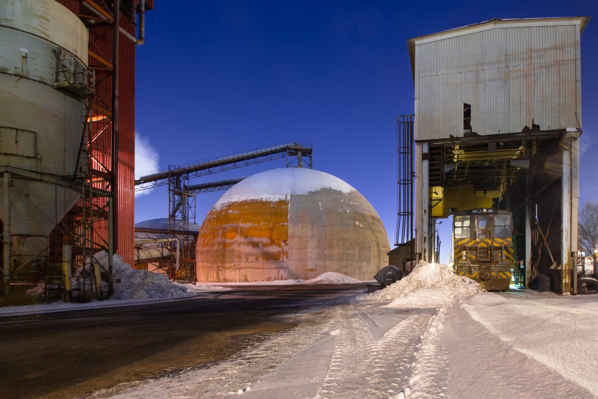 Large metallic dome structure at Upper Harbor Terminal on the Mississippi River in Minneapolis, surrounded by industrial buildings and equipment.
