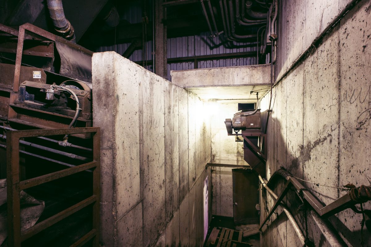 Interior of abandoned Upper Harbor Terminal barge facility showing concrete walls, rusted metal infrastructure, and industrial equipment in Minneapolis.