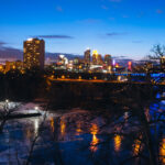 Downtown Minneapolis behind the Mississippi River during blue hour.