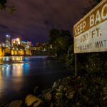 Sign reading "Keep Back 500 FT Turbulent Water" seen on the Mississippi River in Downtown Minneapolis.