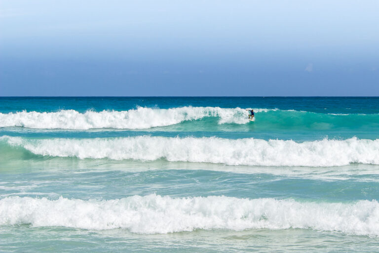 Surfer at Playa Macao 1 A surfer rides a wave at Playa Macao, a public beach located on the northeastern coast of the Dominican Republic. This beach is known for its consistent waves, making it a popular destination for surfers and a significant site for water sports in the region. Playa Macao is situated near the resort town of Punta Cana, offering a natural contrast to the developed tourist areas.