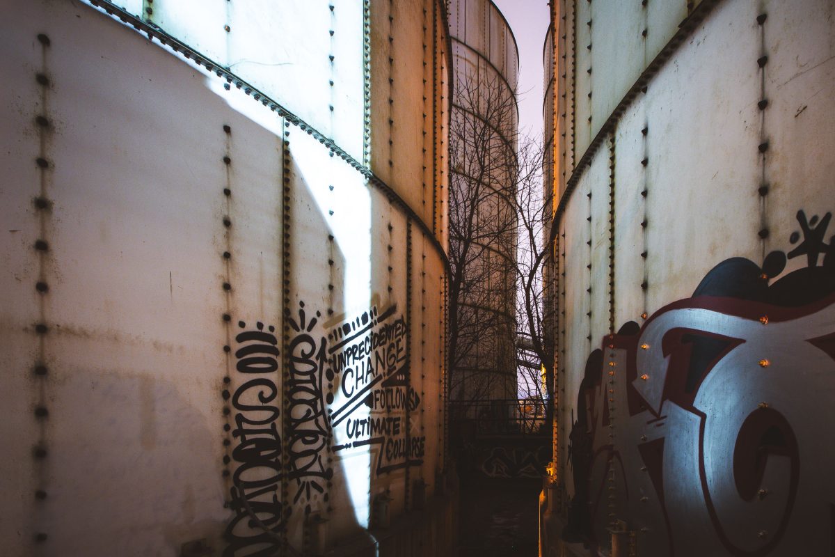 SHOCK graffiti reading "Unprecedented Change Follows Ultimate Collapse" on industrial metal structures at Upper Harbor Terminal in Minneapolis.