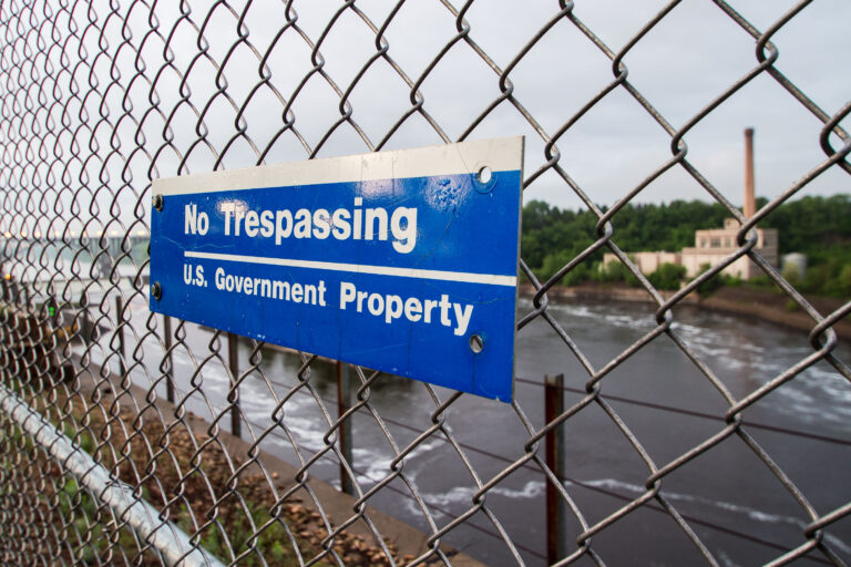 No Trespassing Sign, Mississippi River, St. Paul 1 A "No Trespassing, U.S. Government Property" sign is visible on a chain-link fence overlooking the Mississippi River in St. Paul, Minnesota.