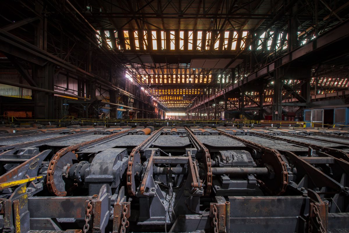 Abandoned steel mill interior with rusted industrial machinery and overhead lighting at ArcelorMittal in East Chicago.