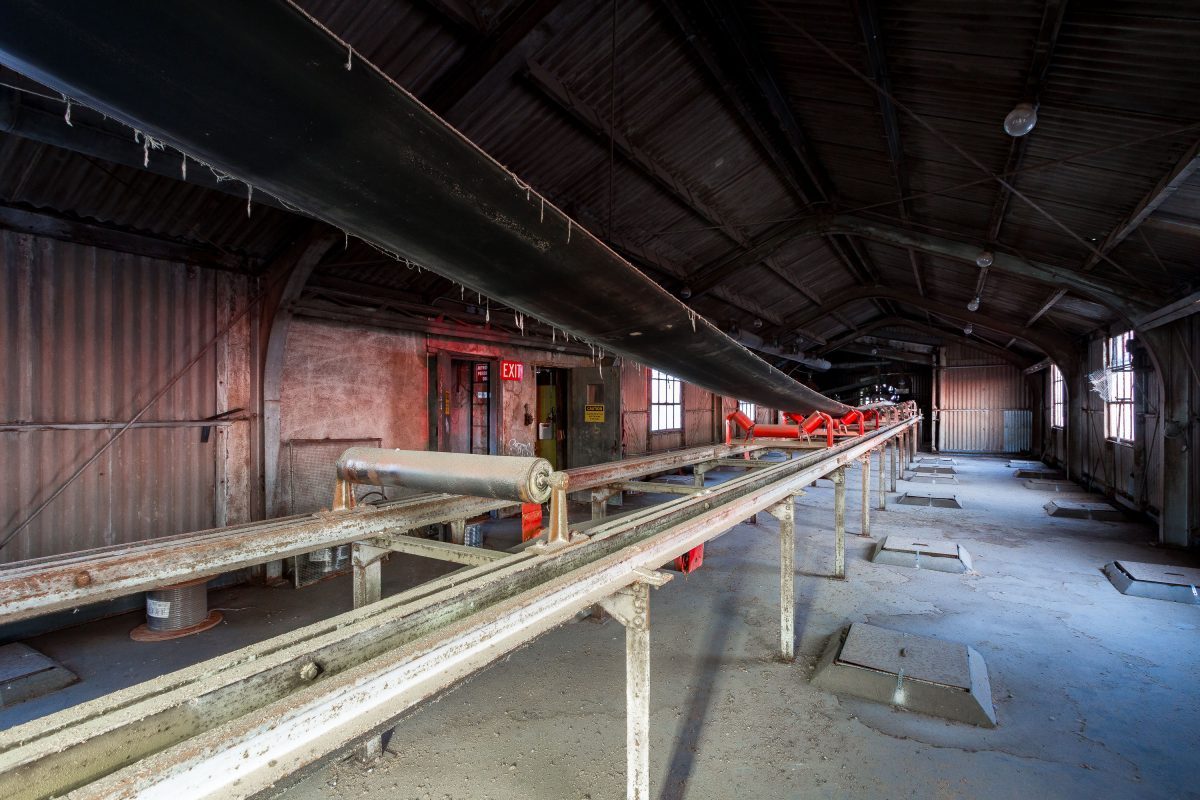 Interior of the Electric Steel Grain Elevator in Minneapolis showing weathered conveyor systems and industrial machinery beneath a metal-beam ceiling.