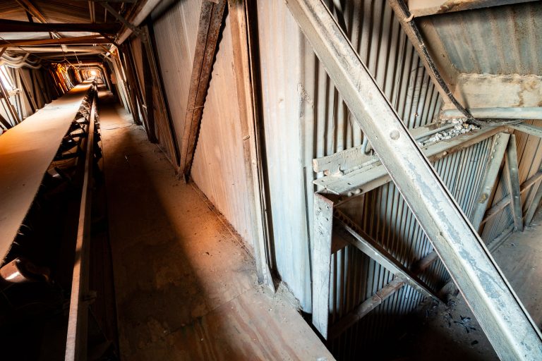 Interior of the Electric Steel grain elevator in Minneapolis showing a rusted conveyor belt and corrugated metal structural framework.