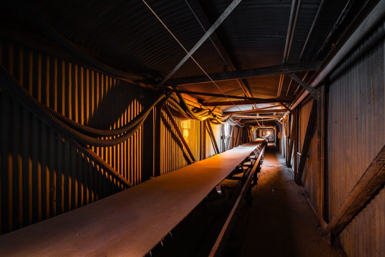 Interior of Electric Steel grain elevator in Minneapolis showing a long conveyor belt beneath industrial metal framework and corrugated walls.