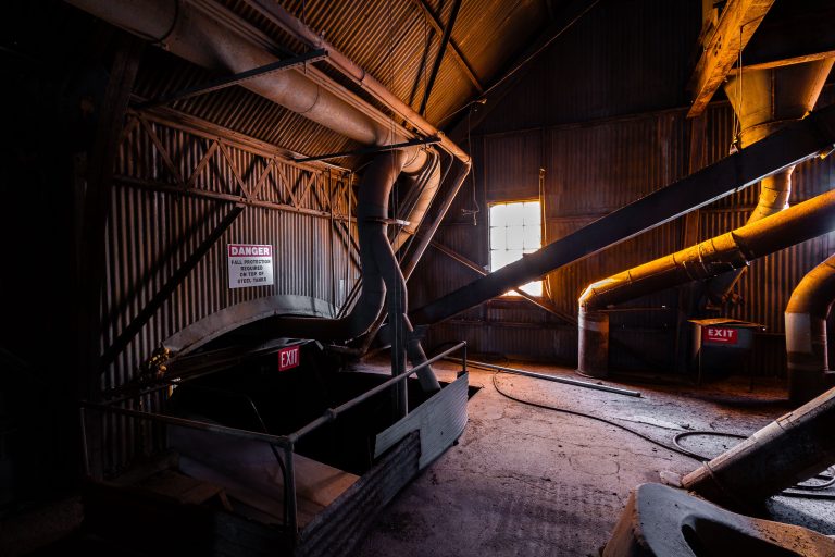 Interior of Electric Steel grain elevator in Minneapolis showing industrial pipes, metal infrastructure, and exit signage.