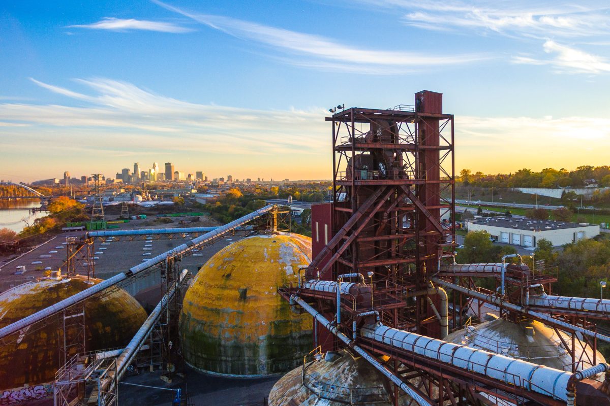 Abandoned Upper Harbor Terminal barge facility on the Mississippi River in north Minneapolis at sunset with industrial storage tanks and loading equipment.