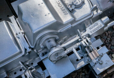 A close-up of an Alstom railway switch machine, showing the locked levers for power and hand-throw operation, used to control train track switches.