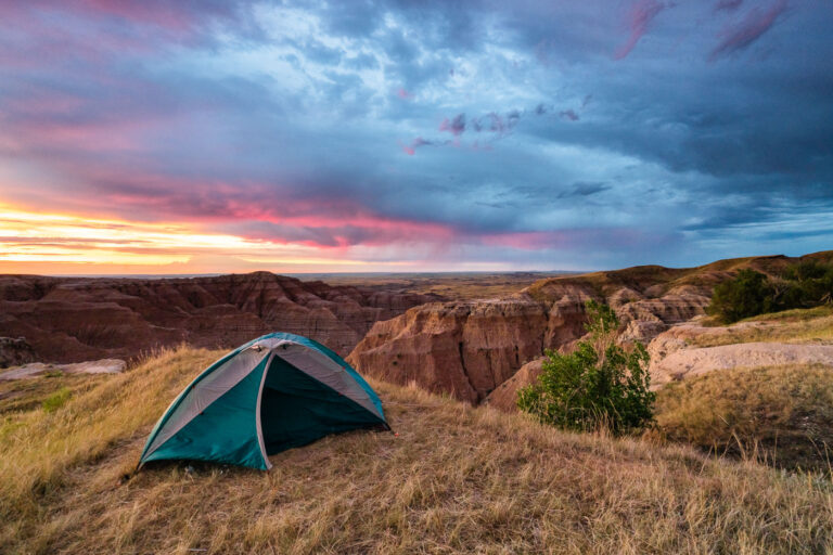 Sunrise Over Tent at Buffalo Gap National Grasslands, South Dakota 4 A tent is pitched on a grassy overlook within the Buffalo Gap National Grasslands in South Dakota, as a dramatic sunrise paints the sky with vibrant colors. This area, managed by the Bureau of Land Management, is known for its rugged badlands topography and expansive prairie landscapes. The grasslands were established in 1960 to conserve and manage the natural grasslands and associated wildlife habitats. Today, it remains a significant area for grazing, conservation, and public enjoyment of its natural beauty.