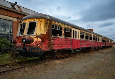 A decommissioned SNCB/NMBS Autorail Série 400, unit no. 4001, rests abandoned on a disused siding near Charleroi, Belgium. Built in the early 1950s by BN (La Brugeoise et Nivelles), these diesel multiple units were among Belgium’s first post-war efforts to modernize regional and intercity rail travel, replacing steam on secondary lines. The streamlined design and two-tone red-and-cream livery reflected the optimism of that era’s industrial renewal. Decades later, this car’s faded paint, shattered windows, and rust-etched steel now mark the slow decay of a machine that once represented progress in Belgian transport history. The surrounding derelict depot underscores the decline of Wallonia’s railway manufacturing heritage.