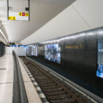 Brandenburger Tor Train Station 4 The Brandenburger Tor station on Berlin’s U5 line sits directly beneath Pariser Platz, adjacent to the Brandenburg Gate. The interior features dark composite wall panels inlaid with gold lettering and a series of illuminated displays tracing Berlin’s 20th-century history, including the city’s division and post-reunification development. Originally opened in 2009 as part of the short U55 shuttle between Hauptbahnhof and Bundestag, the station became a through stop in December 2020 when the U5 extension to Alexanderplatz was completed, reconnecting the eastern and western portions of the U-Bahn network after nearly six decades of separation.