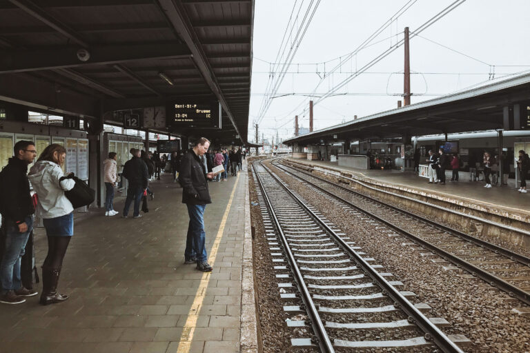 Brussels-Midi Station Platform with Train Tracks 1 Passengers wait on the platform at Brussels-Midi Station, a major international railway hub, with train tracks stretching into the distance.
