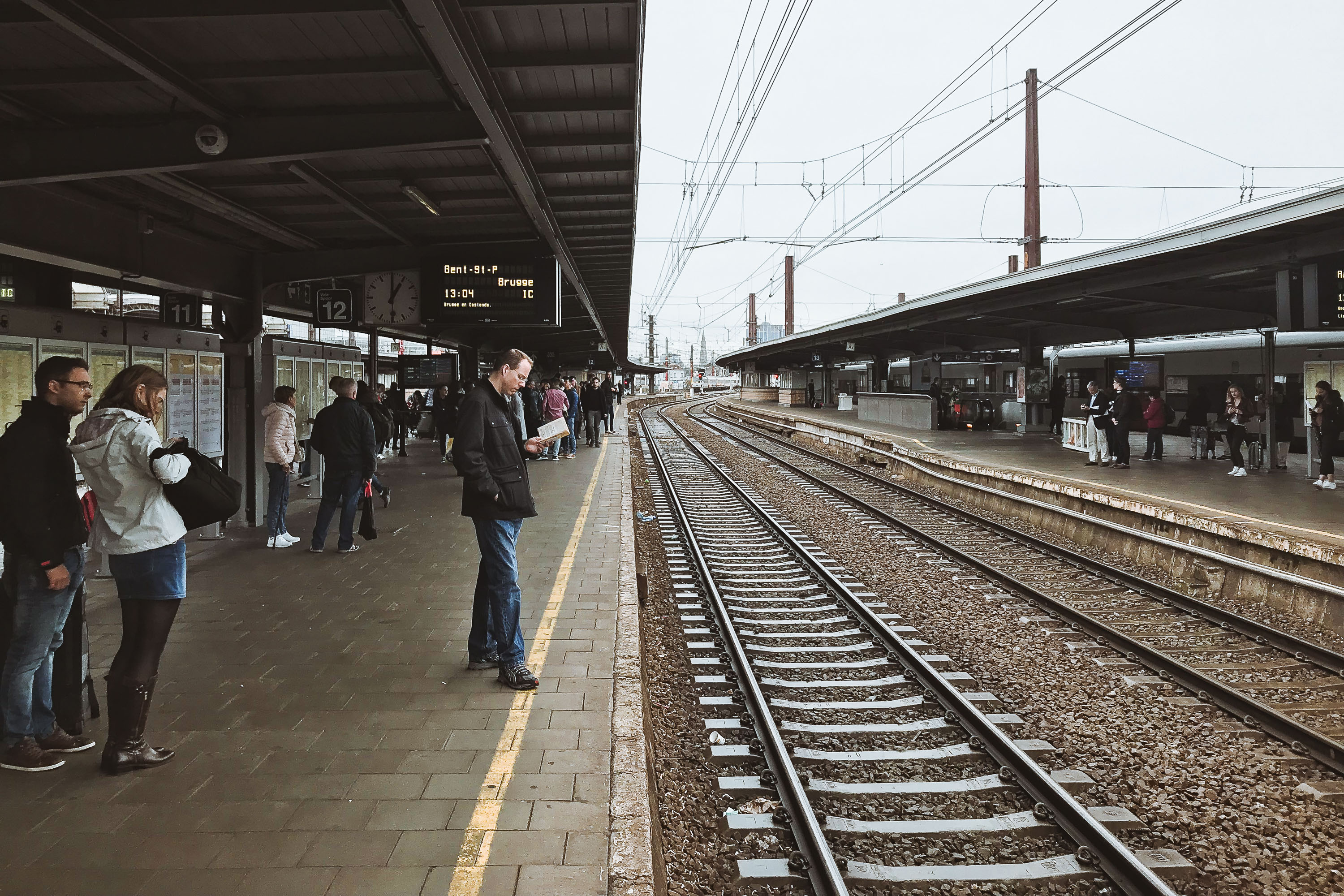 Brussels-Midi Station Platform with Train Tracks 3 Passengers wait on the platform at Brussels-Midi Station, a major international railway hub, with train tracks stretching into the distance.