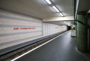 Kurt-Schumacher-Platz station serves Berlin’s U6 U-Bahn line in the Reinickendorf district, located in the city’s northwest. Opened on May 3, 1956, the station was part of the first postwar U-Bahn expansion and named after German statesman Kurt Schumacher, a key figure in rebuilding the Social Democratic Party after World War II.

The station features light-colored wall tiles with horizontal gray stripes and minimalist red lettering, reflecting mid-1950s West Berlin design. It includes a central island platform and two tracks, serving as an important stop between Afrikanische Straße and Scharnweberstraße. Above ground, the station connects to several bus routes and lies near the approach to the U6 tunnel under the former Tegel Airport area. Today, it remains a key link for northern Berlin commuters traveling toward the city center.