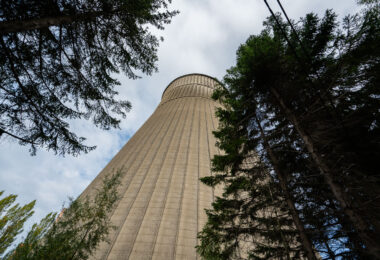 A 118-meter-tall cooling tower stands amid overgrown trees at the former Monceau-sur-Sambre power station near Charleroi, Belgium. Constructed in the 1960s as part of a large coal-fired generating complex operated by Electrabel, the hyperboloid structure was engineered from reinforced concrete with vertical ribbing to support its weight and withstand wind pressure. The tower once cooled thousands of cubic meters of water per hour, discharging excess heat from the station’s turbines that supplied electricity to the industrial Walloon region. Following the plant’s closure in the early 2000s, the site has remained disused, its monumental scale and weathered surface now emblematic of Charleroi’s industrial decline and gradual environmental recovery.