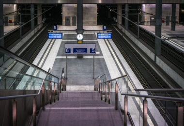 The lower platforms of Berlin Hauptbahnhof, serving tracks 5 and 6, form part of the deep-level north–south route opened with the station in 2006. This subterranean level, approximately 15 meters below ground, connects long-distance ICE services between Hamburg, Leipzig, and Munich through the Tiergarten Tunnel. The design reflects the precision and uniformity of modern German rail architecture—clean concrete forms, stainless steel fixtures, and bright LED signage. The symmetrical layout, glass partitions, and central clock emphasize efficiency and clarity, key elements of the Hauptbahnhof’s function as Europe’s largest crossing-station hub.