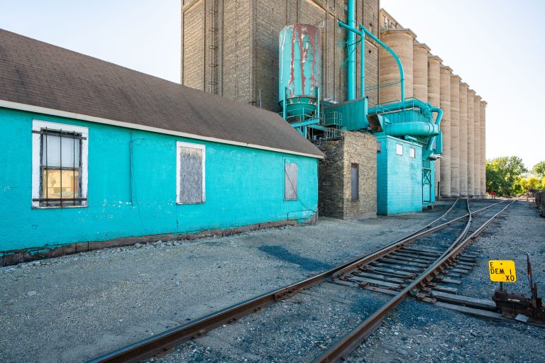 Turquoise grain elevator and outbuilding with railroad tracks in Minneapolis.