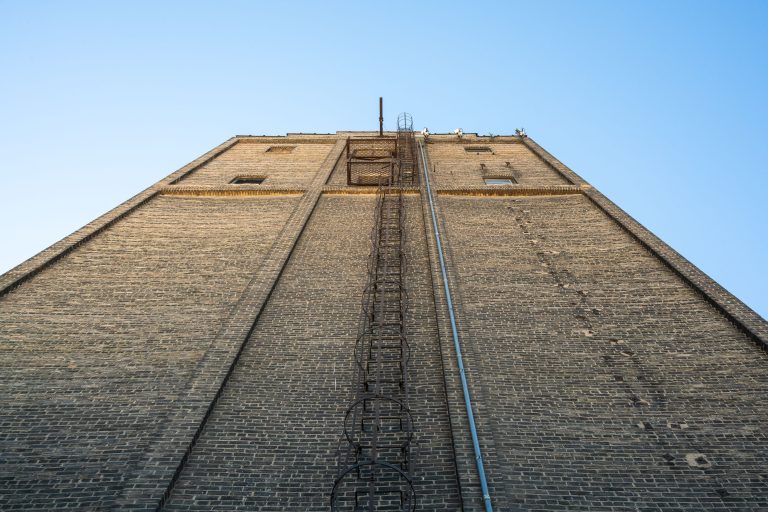 Viterra Grain Elevator, Minneapolis 4 Upward view of a tall brick grain elevator with metal fire escape and utility lines in Minneapolis.