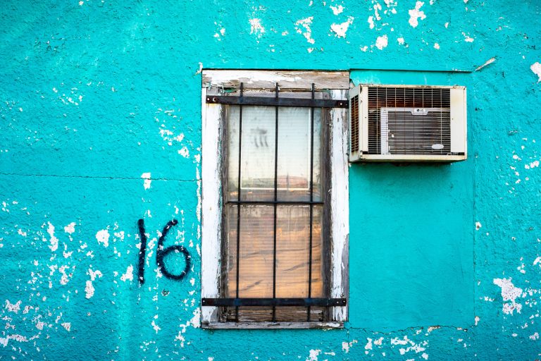 Window 16, Viterra Grain Elevator, Minneapolis 4 Turquoise painted wall with peeling white paint, barred window, air conditioning unit, and graffiti marking.
