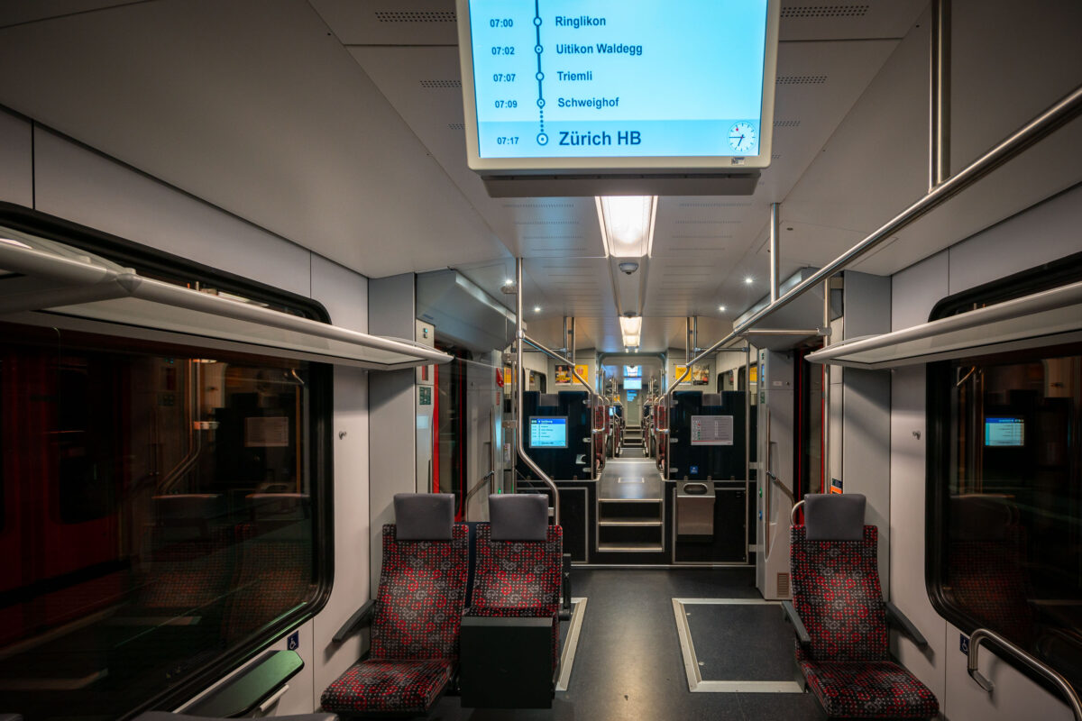 Interior of a Zürich S-Bahn train heading to Zürich HB, Switzerland's main railway station, showcasing functional design and efficient public transport.