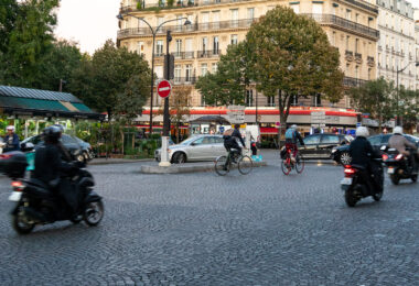 Evening commuters navigate the cobblestone intersection at Place de l’Alma, a busy roundabout near the Seine that connects several major Parisian avenues. Cyclists, scooters, and cars intermingle beneath the façades of Haussmann-era buildings, a familiar rhythm in the city’s daily life. The area blends elegance and intensity—its limestone balconies and cafés standing in contrast to the constant motion of urban transit.

Completed in the mid-19th century, Place de l’Alma became a symbolic gateway between the Right Bank and the Left, linking the fashionable avenues of the 8th and 16th arrondissements. The nearby Pont de l’Alma, inaugurated in 1856 by Napoleon III, was once guarded by four statues of French soldiers—only one, the Zouave, remains today, still serving as an informal flood gauge for the rising Seine.