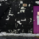 An emergency exit door on top of a Minneapolis parking ramp. Paint peeling on the walls.