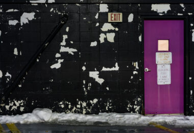 An emergency exit door on top of a Minneapolis parking ramp. Paint peeling on the walls.