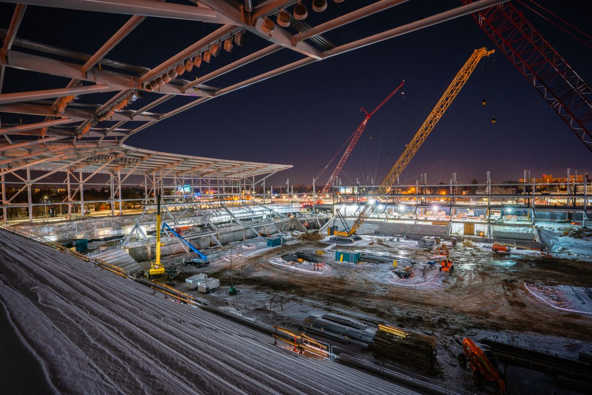 Nighttime construction site of Allianz Field stadium in St. Paul with illuminated steel framework and cranes.