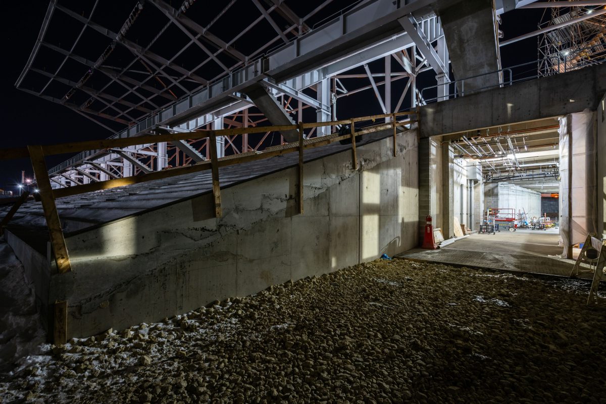 Nighttime construction site of Allianz Field stadium in St. Paul showing concrete foundation, steel framework, and illuminated
