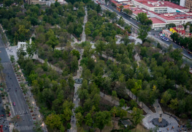 An aerial view of Alameda Central, Mexico City’s oldest public park, established in 1592 and redesigned in the 19th century in the European style. The white semicircular monument visible on the left is the Hemiciclo a Juárez, erected in 1910 to honor President Benito Juárez. The park’s grid of walkways, fountains, and neoclassical sculptures serves as a green centerpiece of the Centro Histórico, surrounded by civic and cultural landmarks like the Palacio de Bellas Artes.