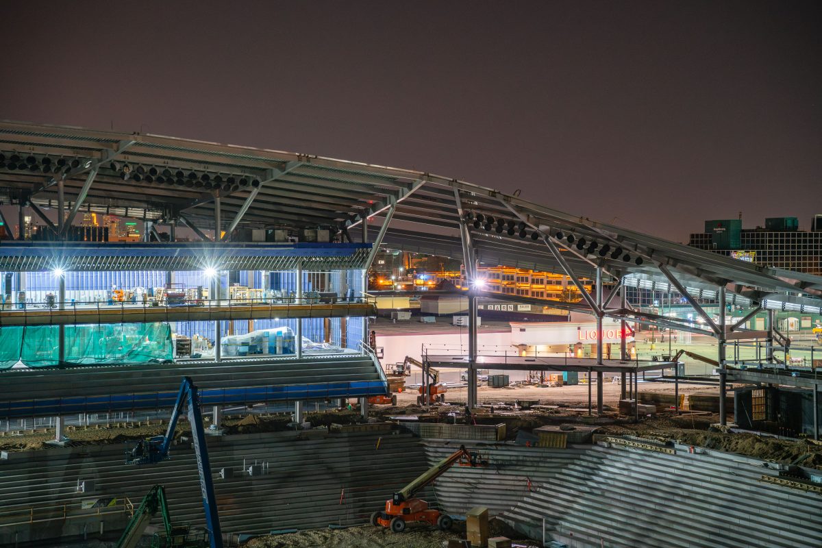 Allianz Field stadium under construction at night in St. Paul with excavated ground and illuminated steel framework.