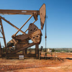 A weathered pumpjack rises from the red clay of western North Dakota, slowly rocking under the midday sun. Once a quiet symbol of rural industry, it now stands as a reminder of the region’s deep ties to oil production and the changing energy landscape of the American Plains.