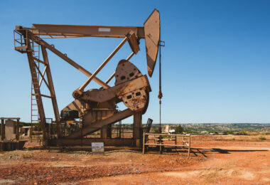 A weathered pumpjack rises from the red clay of western North Dakota, slowly rocking under the midday sun. Once a quiet symbol of rural industry, it now stands as a reminder of the region’s deep ties to oil production and the changing energy landscape of the American Plains.