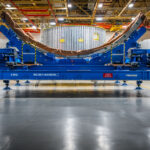 Precision barrel tooling used in the assembly of the Space Launch System (SLS) core stage stands on the production floor at NASA’s Michoud Assembly Facility in New Orleans. These fixtures hold massive aluminum panels in place during the friction stir welding process, ensuring perfect alignment and uniform curvature for the rocket’s cylindrical sections. Behind the tooling, the metallic structure of a completed barrel segment can be seen, ready for the next stage of integration.