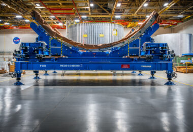 Precision barrel tooling used in the assembly of the Space Launch System (SLS) core stage stands on the production floor at NASA’s Michoud Assembly Facility in New Orleans. These fixtures hold massive aluminum panels in place during the friction stir welding process, ensuring perfect alignment and uniform curvature for the rocket’s cylindrical sections. Behind the tooling, the metallic structure of a completed barrel segment can be seen, ready for the next stage of integration.