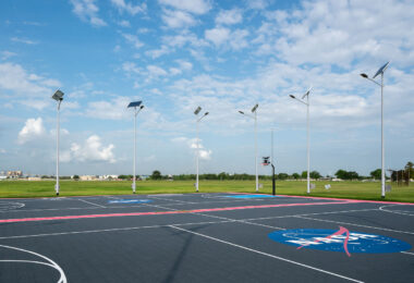 A recreational basketball court at NASA’s Michoud Assembly Facility in New Orleans features the NASA insignia at center court and solar-powered lighting along its perimeter. The court sits on the expansive campus where large-scale aerospace hardware is built, including rocket stages and spacecraft components. Michoud, once known for producing the Saturn V and Space Shuttle external tanks, remains an active center for both engineering and community life for NASA employees and contractors.