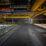 An elevated view of the overhead gantry crane system inside NASA’s Michoud Assembly Facility in New Orleans. These yellow steel cranes are used to lift and maneuver rocket sections, including the massive Space Launch System core stages, within the cavernous production hall. The network of platforms, rails, and suspended hooks demonstrates the industrial scale of spacecraft manufacturing that has taken place here since the Apollo and Space Shuttle programs.