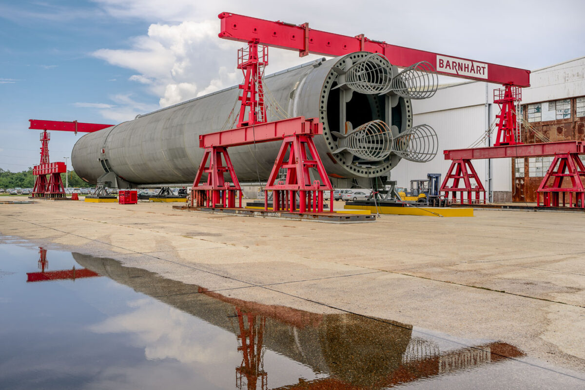A model SLS rocket outside the NASA Michoud Assembly Facility. The model was used to test transporting on the NASA barge.