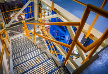 A stairwell winds through the interior of NASA’s Vertical Assembly Center at the Michoud Assembly Facility in New Orleans. The industrial structure, with its orange and blue framework, provides access to various levels of the 170-foot-tall welding system used to assemble core stages of the Space Launch System. The facility supports precision manufacturing for the Artemis program’s heavy-lift rockets.