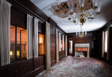 A chandelier and fireplace in the room of an abandoned downtown bank.