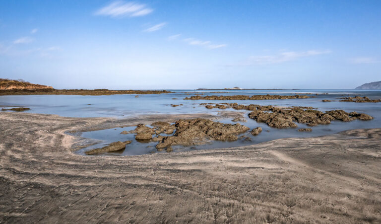 Rocky Shoreline and Tidal Pools, Coastal Gujarat 1 Rocky shoreline and tidal pools on the coast of Gujarat, India, during low tide, showcasing the intertidal zone and marine ecosystems.
