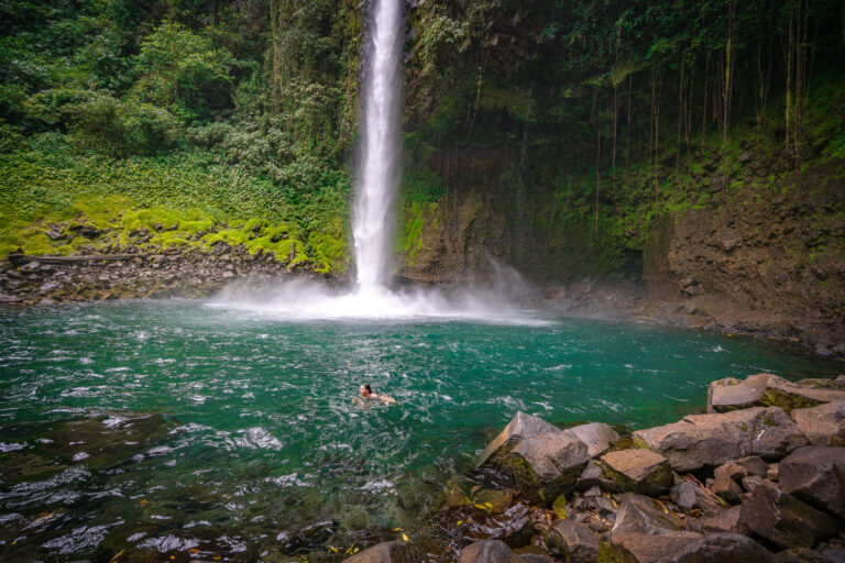 La Fortuna Waterfall Swimming, Costa Rica 4 A person swims in the pool at the base of La Fortuna Waterfall in Costa Rica, surrounded by lush tropical rainforest.