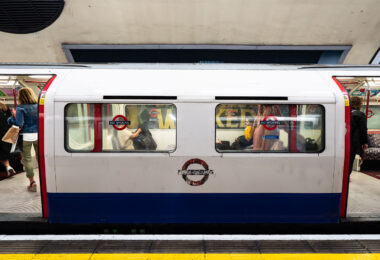 A Bakerloo Line train pauses at Charing Cross Underground Station, one of the most historically layered stations in central London. Opened in 1906, Charing Cross became a key interchange point connecting the Bakerloo and Northern lines beneath the Strand. The photograph captures the distinctive orange-tiled tunnel portal and overhead “Way Out” signage leading toward the mainline station above. Once part of the Jubilee Line until 1999, this section now serves as a terminus for Bakerloo trains, blending Edwardian design elements with the operational systems of a 21st-century network.